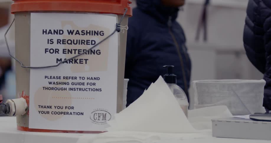 A bucket on the table reads hand washing is required