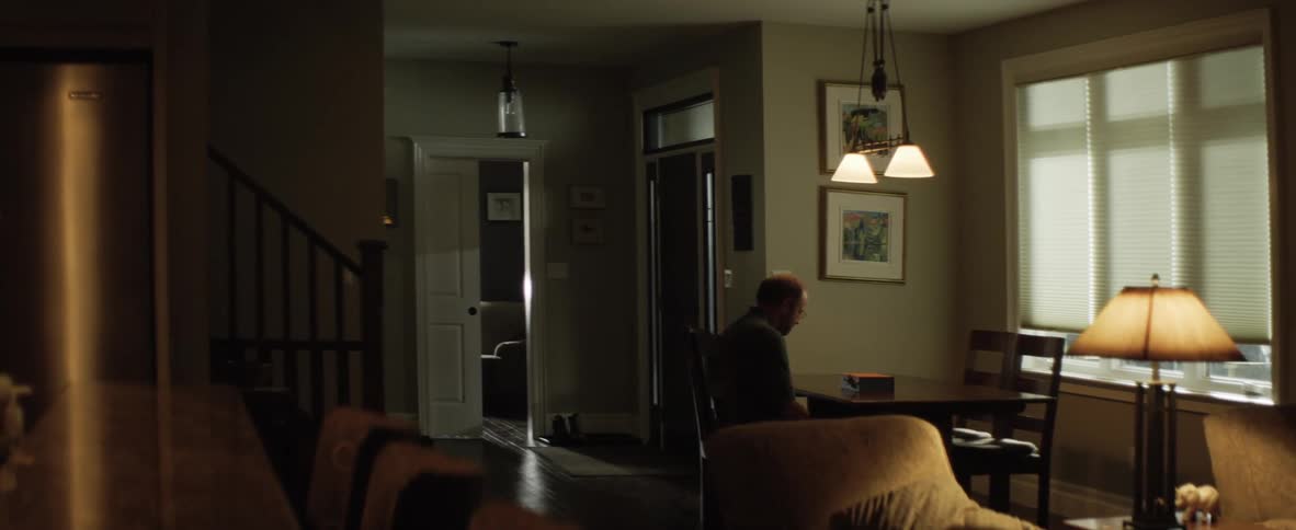 A man sits by himself at a small dining table where he looks at a small box