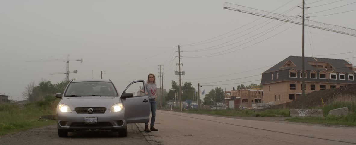 A girl walks to the front of her car