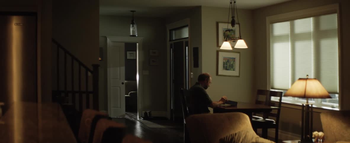 A man fiddling with a box shaped device while sitting at a table indoors