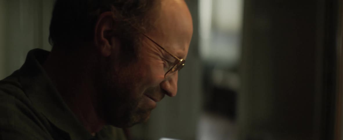 A man laughs and gets emotional while staring down at something