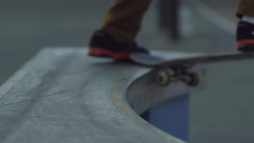 A boy uses his skateboard to jump up on a ledge then falls off