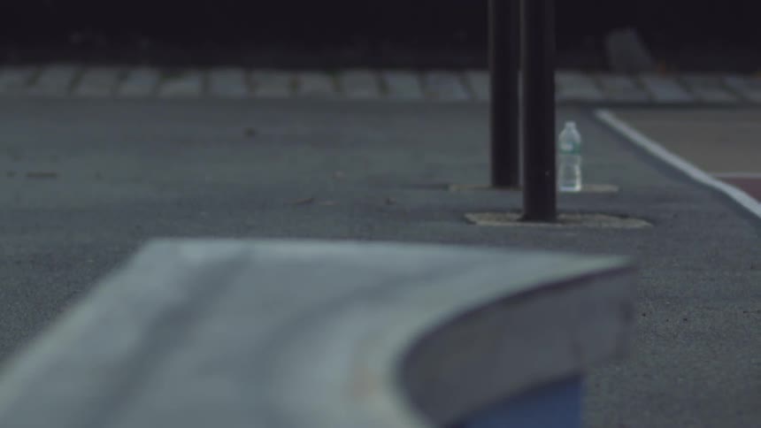 A man in a blue shirt skateboards near a bench