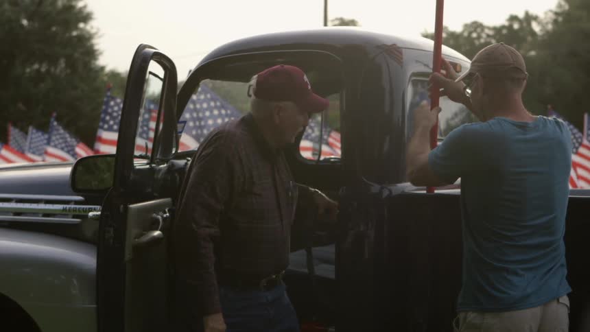 A man places a flag on another mans truck