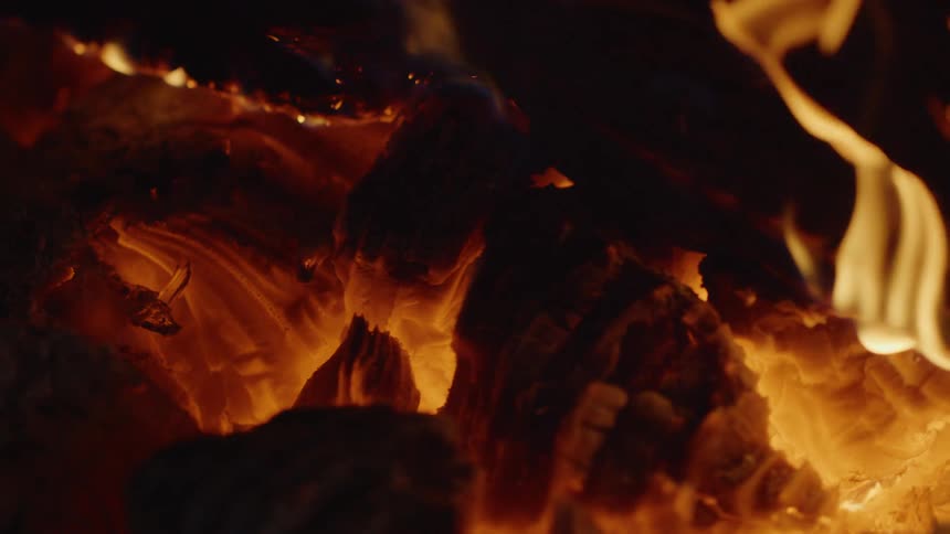 Flames arise and flicker from a burning piece of glowing hot wood