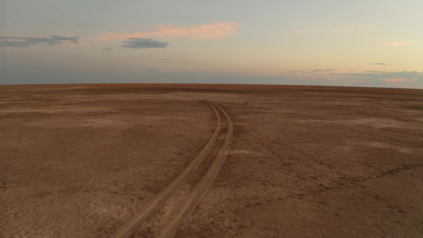 Curving tracks through a barren landscape at sunset