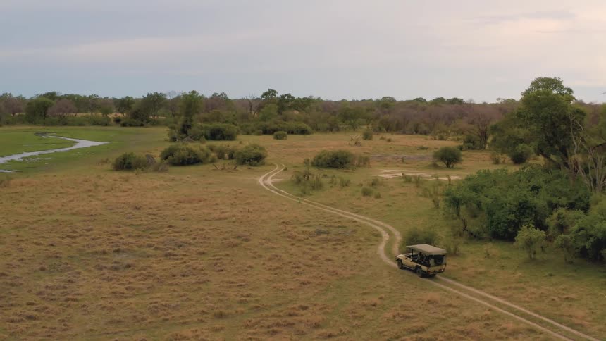 An open style suv drives along a dirt path road next to a river