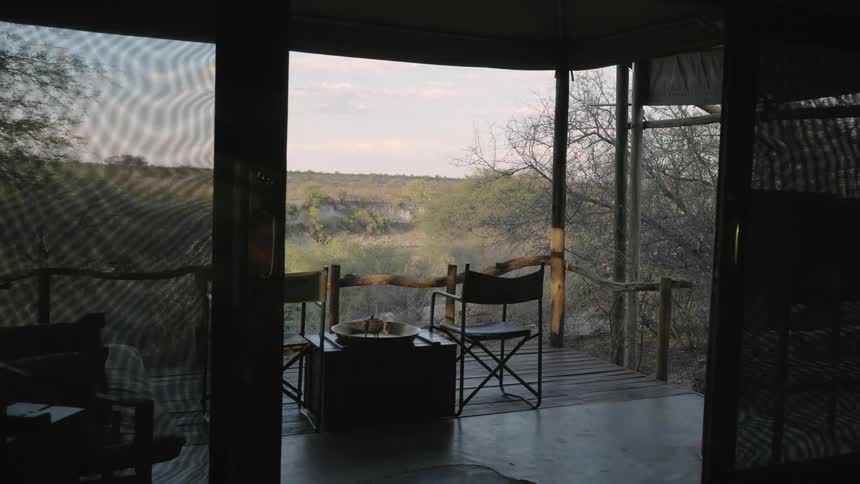 Open doors lead to balcony overlooking hills and fields