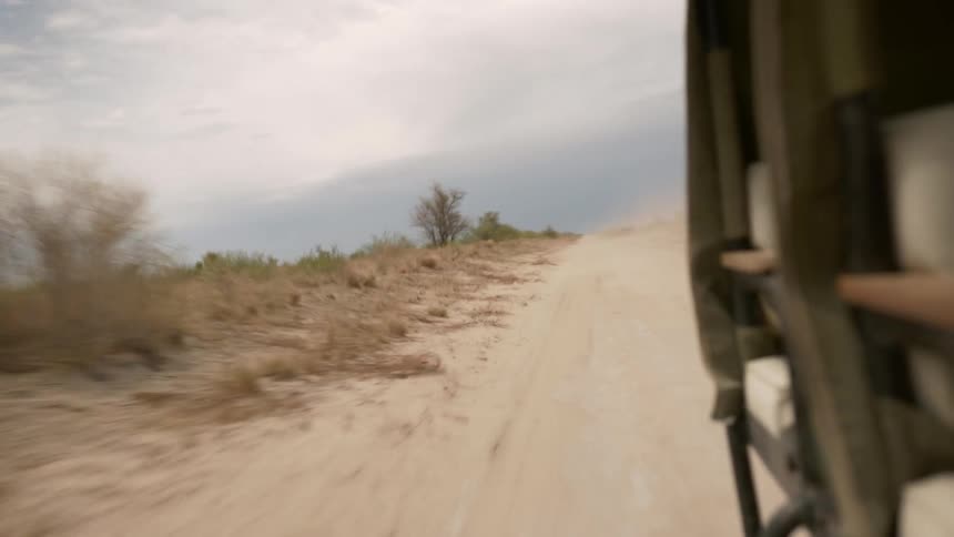 Vehicle drives along dirt road through arid countryside