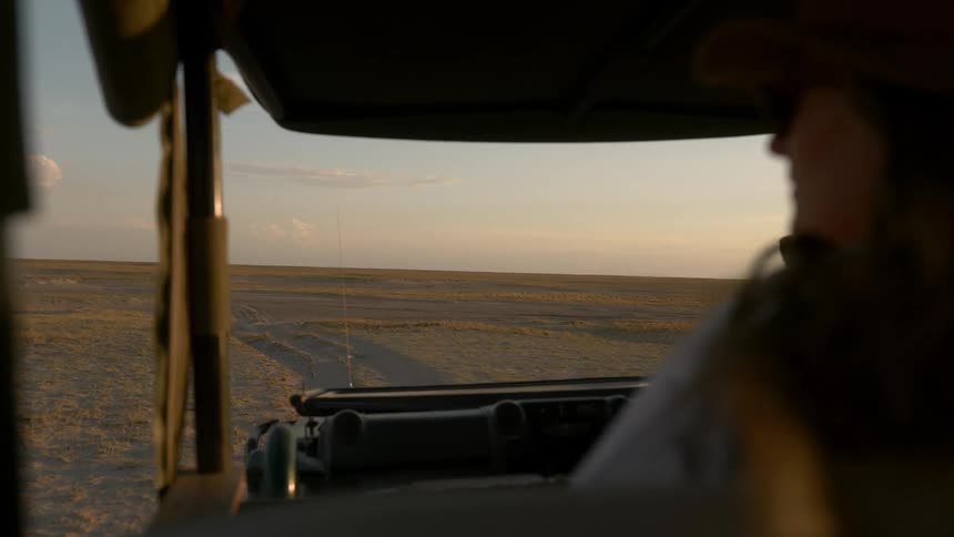 Woman drive along dirt road on plain with window open
