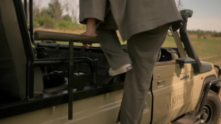 A woman climbs the a step to get into a jeep customized for viewing wildlife