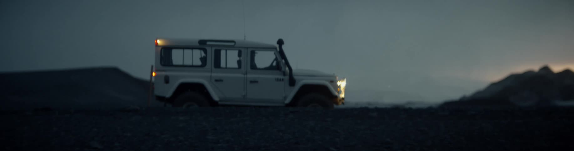 A person drives a vehicle at night and someone runs along the road