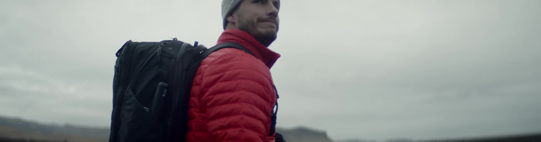 A man with a backpack walks along with his camera