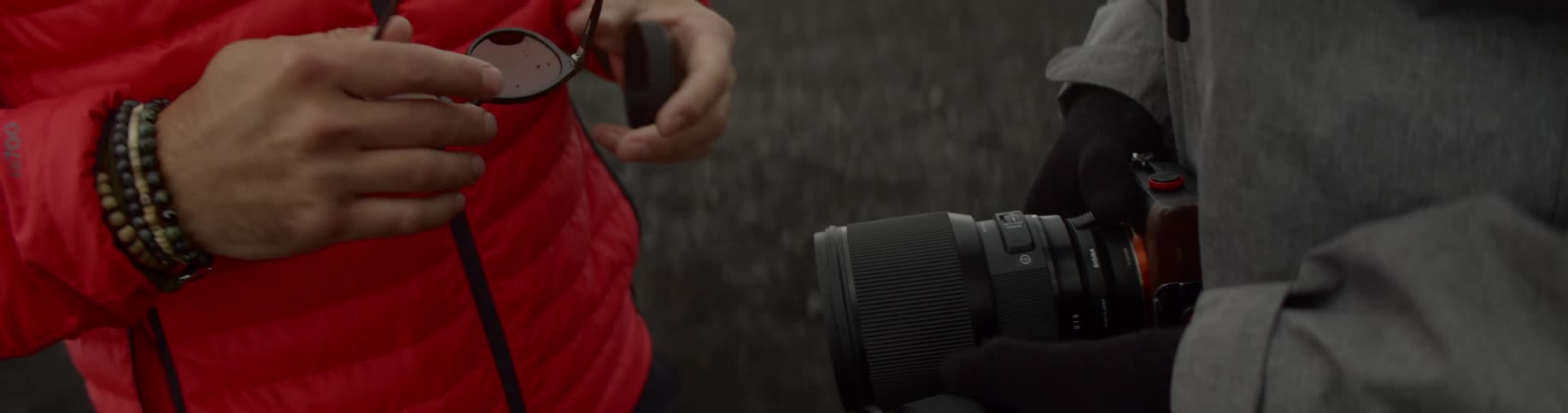 A man fixes a camera lens that someone else is holding