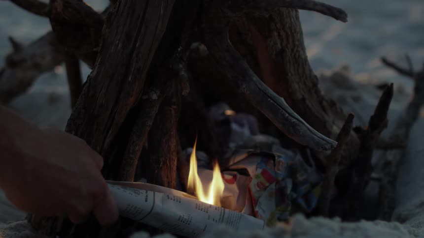 A person lights a fire on the beach