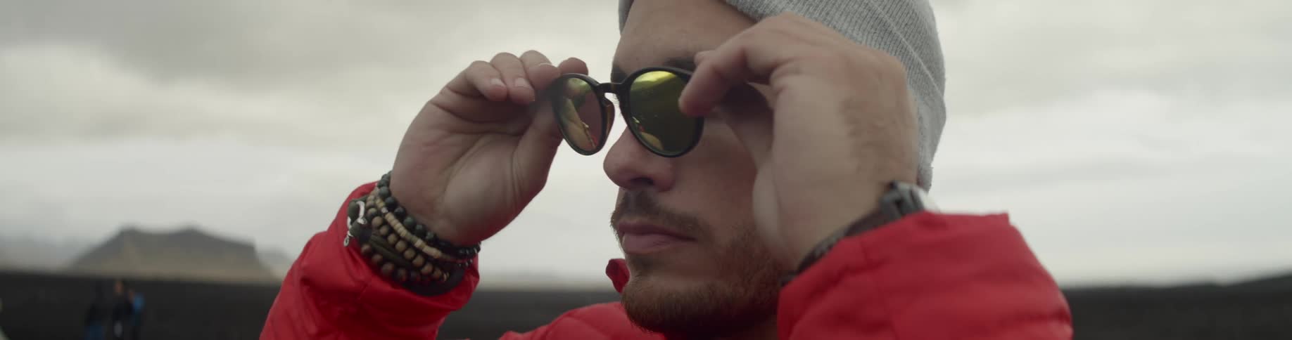 A man puts on sunglasses outside