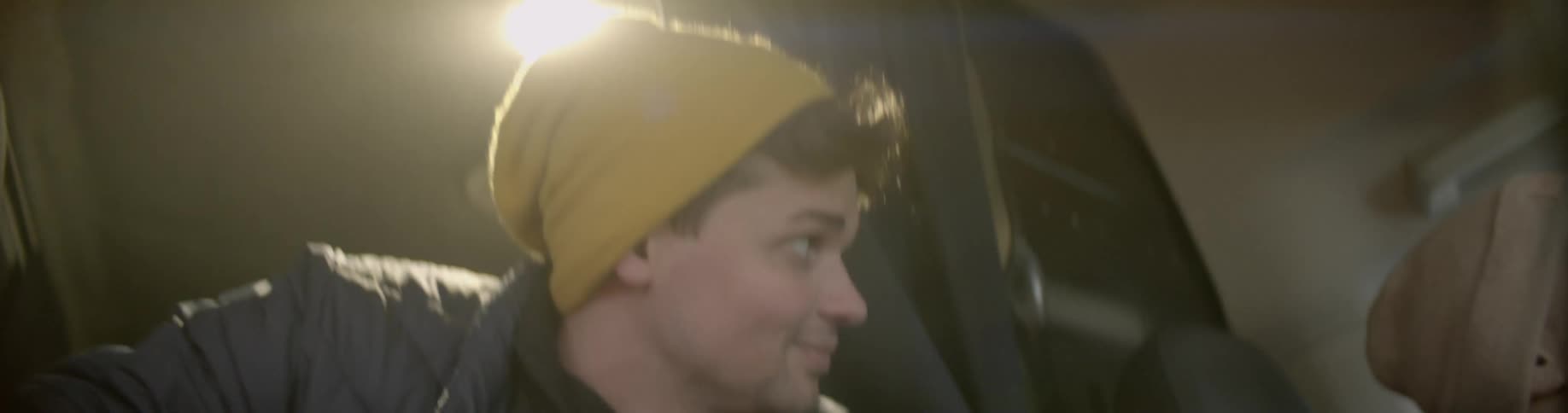A man smiles as he rides in the back of a van