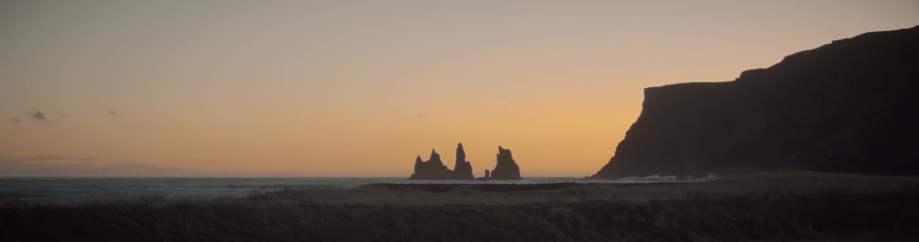 Cliffs and large rocks in ocean at sunset