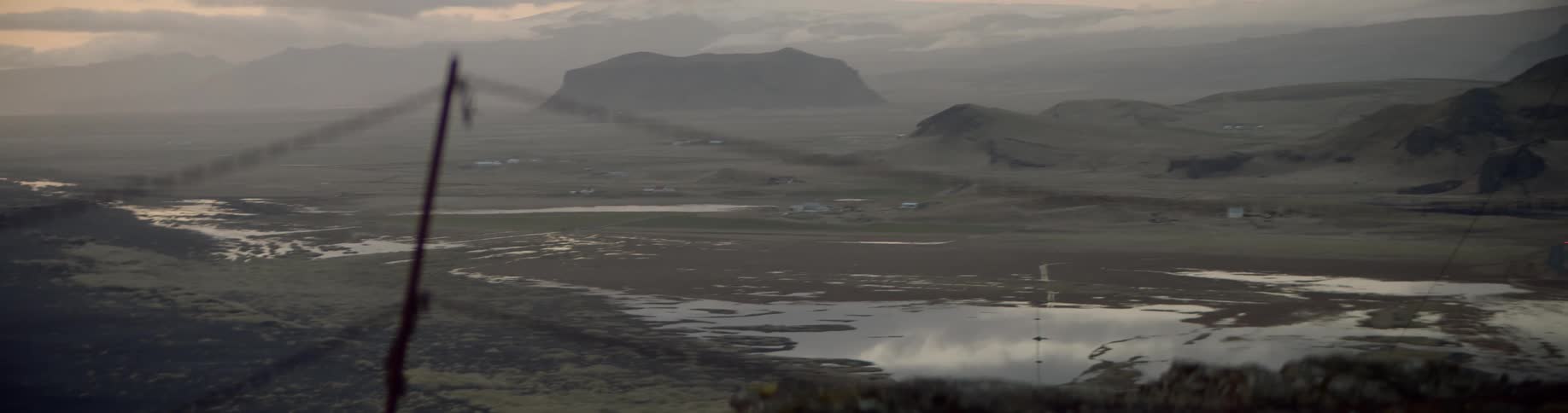 A shoreline and large puddles of water in an open field