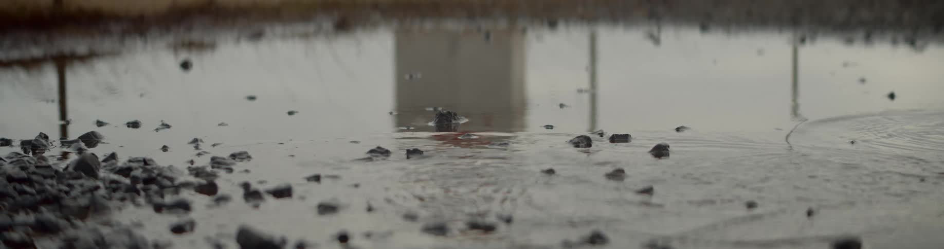 Person walks through puddle disturbing reflection