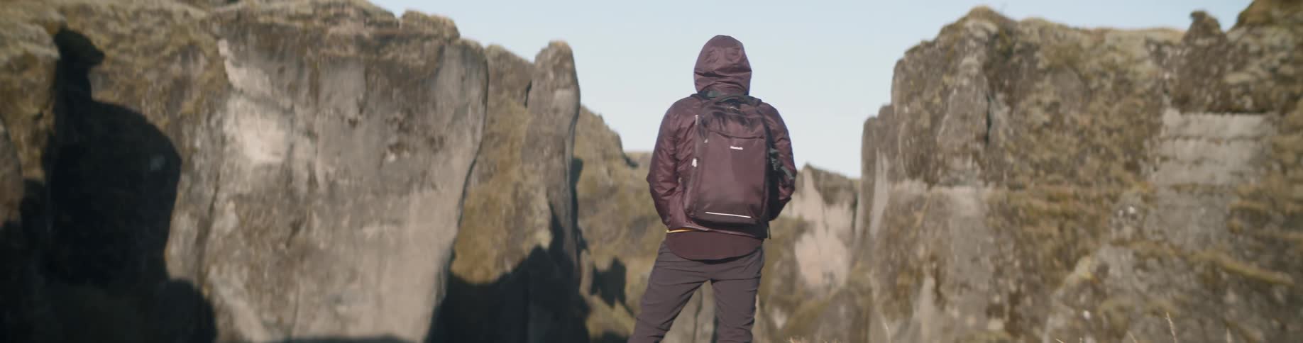 A photographer takes a picture while hiking in mountains with a backpack