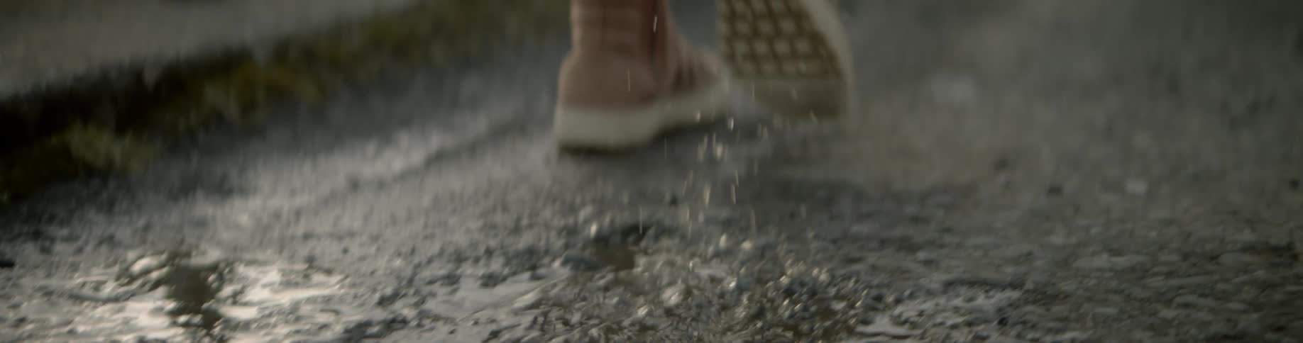 A woman walks through puddles in the street