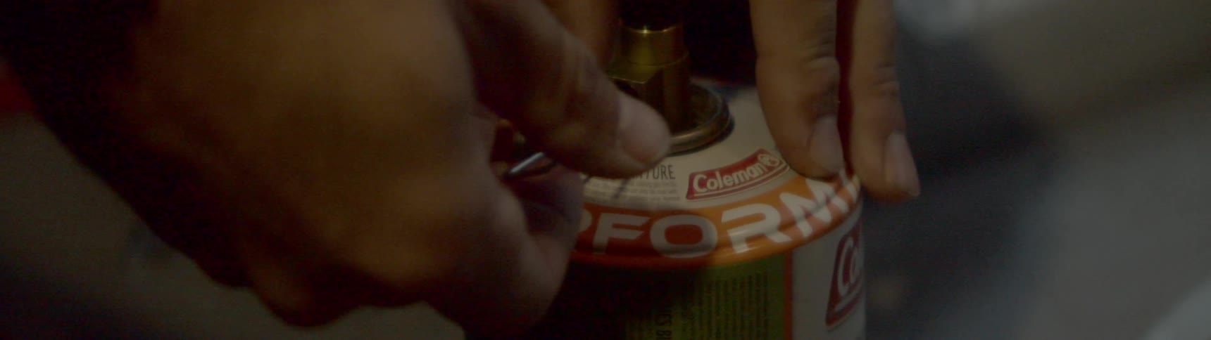 A person unscrews a knob on a propane tank