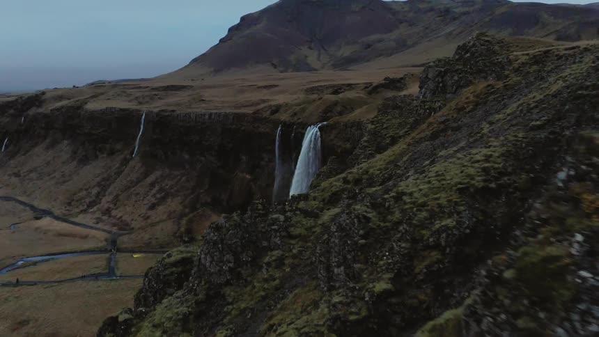 Aerial view of a waterfall flowing over a hill in to a river below