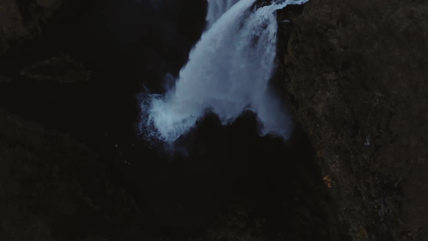 A waterfall crashes down a cliff in to the water below