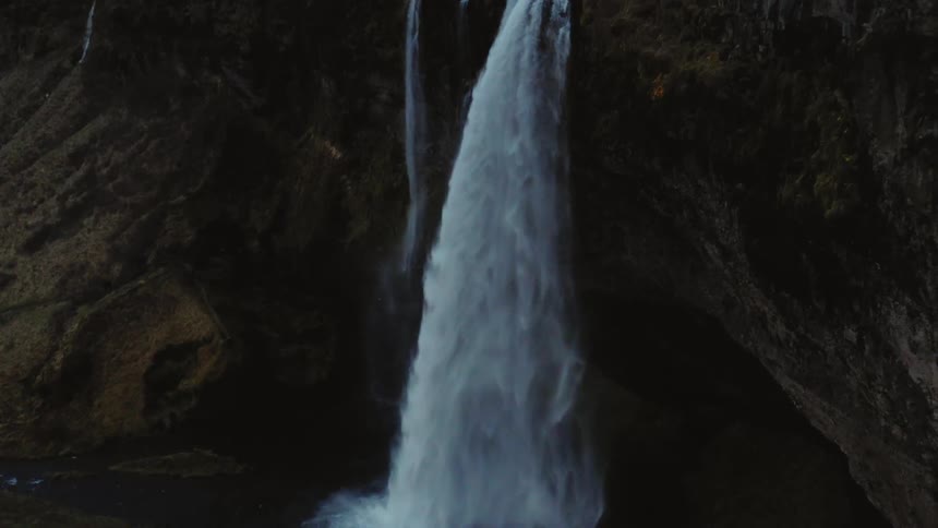 The waterfall pours off the cliff