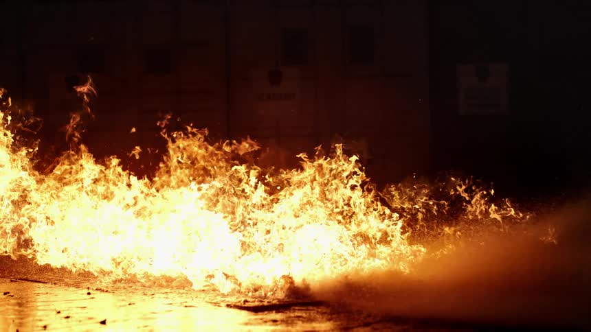 A large fire burns as water is sprayed on it