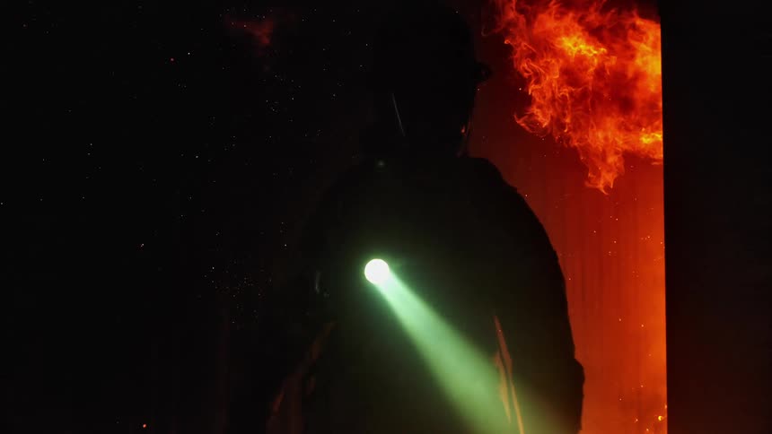 A firefighter moves through a burning building