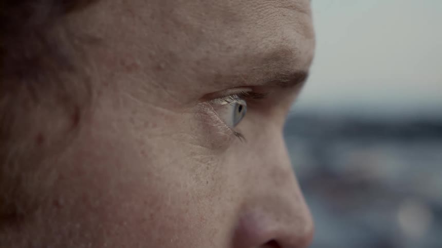 The man blinks his eyes and looks away outdoor