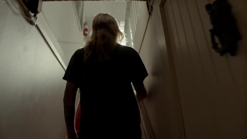 Male walking through narrow hallway then up the stairs to main living area