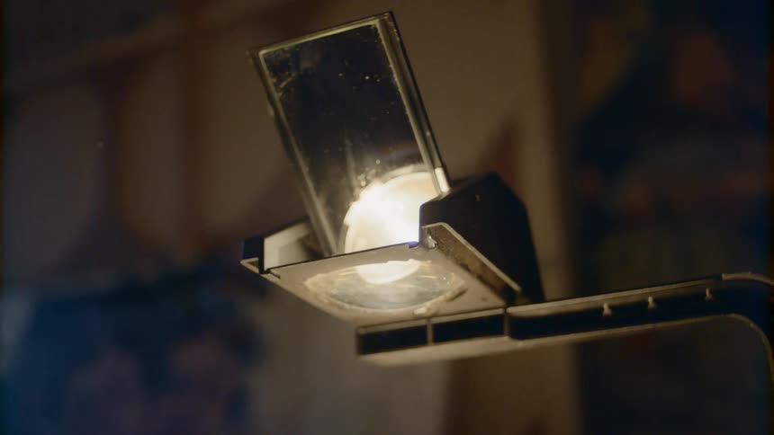 A cell phone rests in a moving arm while a light shines