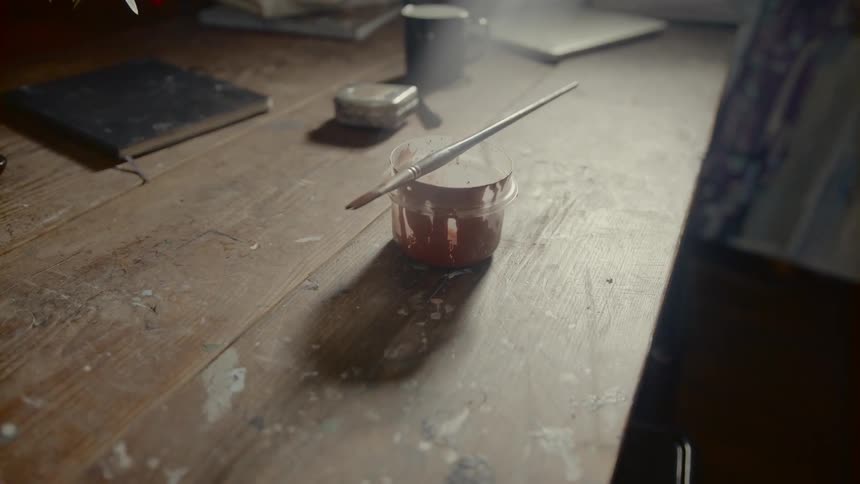 A table with a container and a paint brush on it