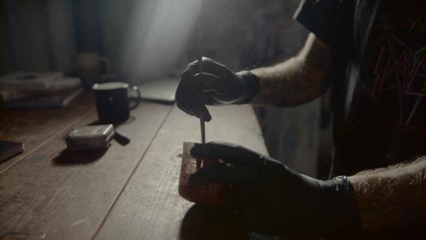 A man uses a paint brush to mix something in a bowl