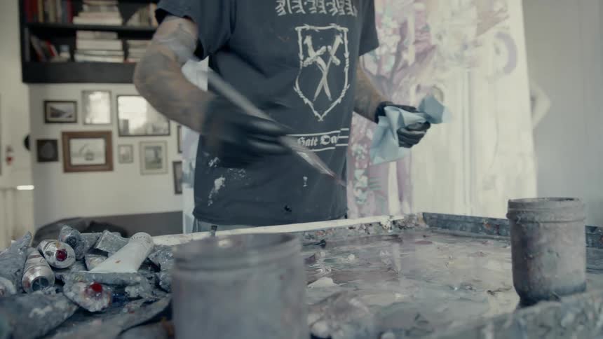 Artist cleans paint brushes over work table