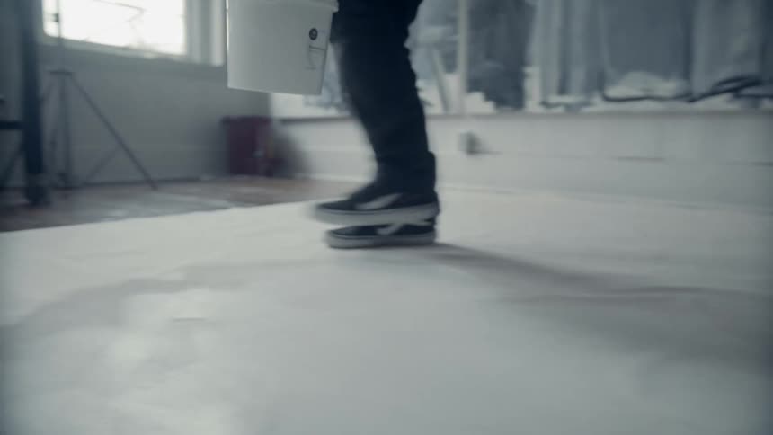 A man with a paintbrush and a paint bucket painting the floor