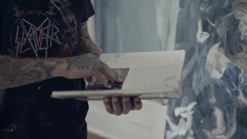 Man with tattoos flips through book