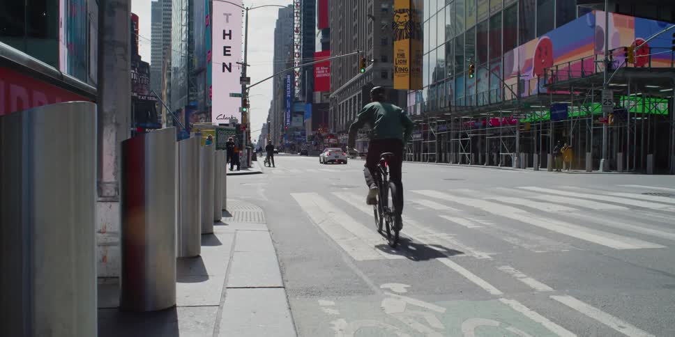 A man sits on a bicycle and waits to cross the street