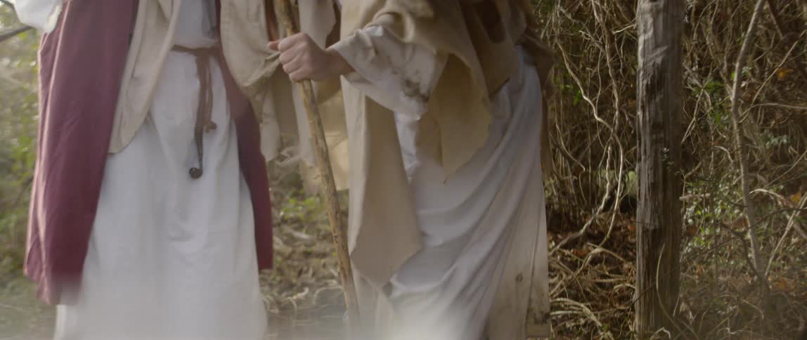 One man in robes helps other to stand up from the ground