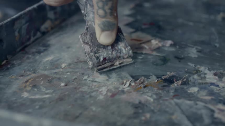 A man uses a putty knife to scrape a surface