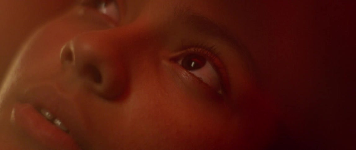 A closeup shows a young womans face as she opens her eyes and looks upwards