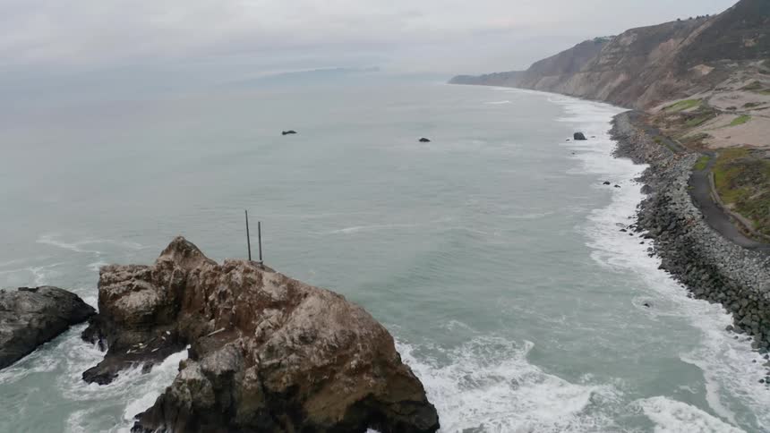 Aerial of waves gently lapping against cliff side shoreline