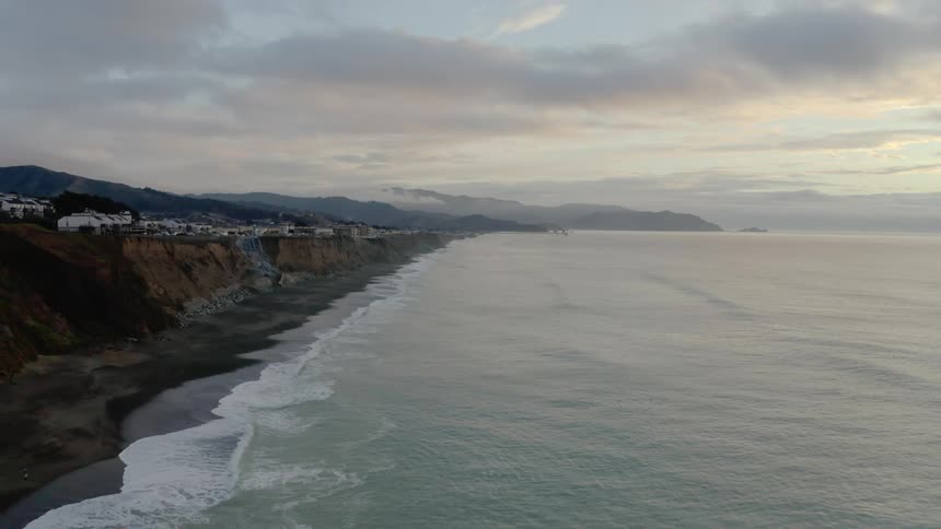 A long coastal shore is lined with beaches and cliffs that have multiple residences atop it