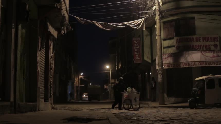 A man pushes a food card through the street at night