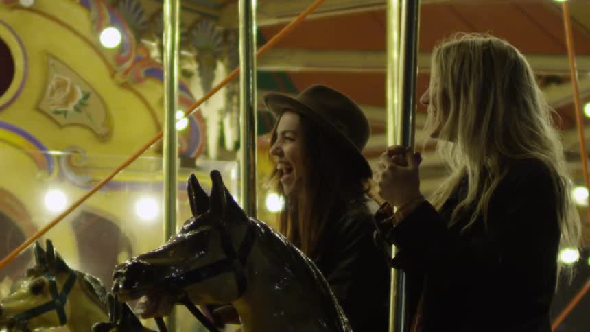 Two women laugh as they ride a carousel
