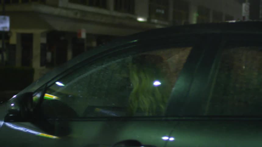 A man opens the car for a woman who gets in and buckles her seat belt