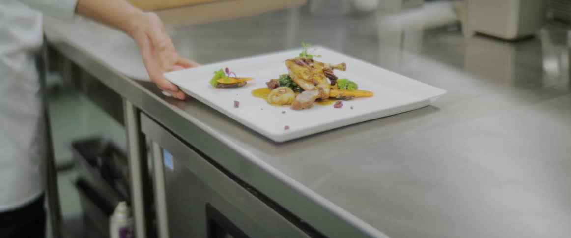 A chef places a dish on the counter